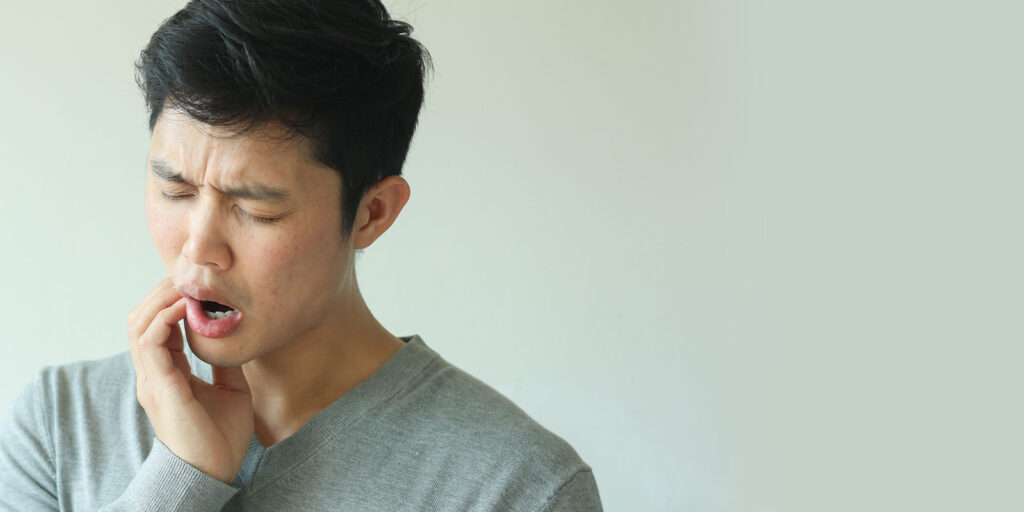 man holding jaw in pain
