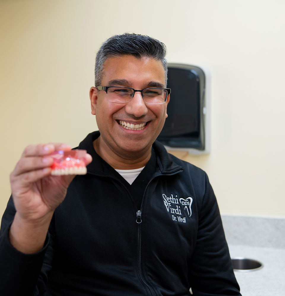 Doctor holding up model of dental implants
