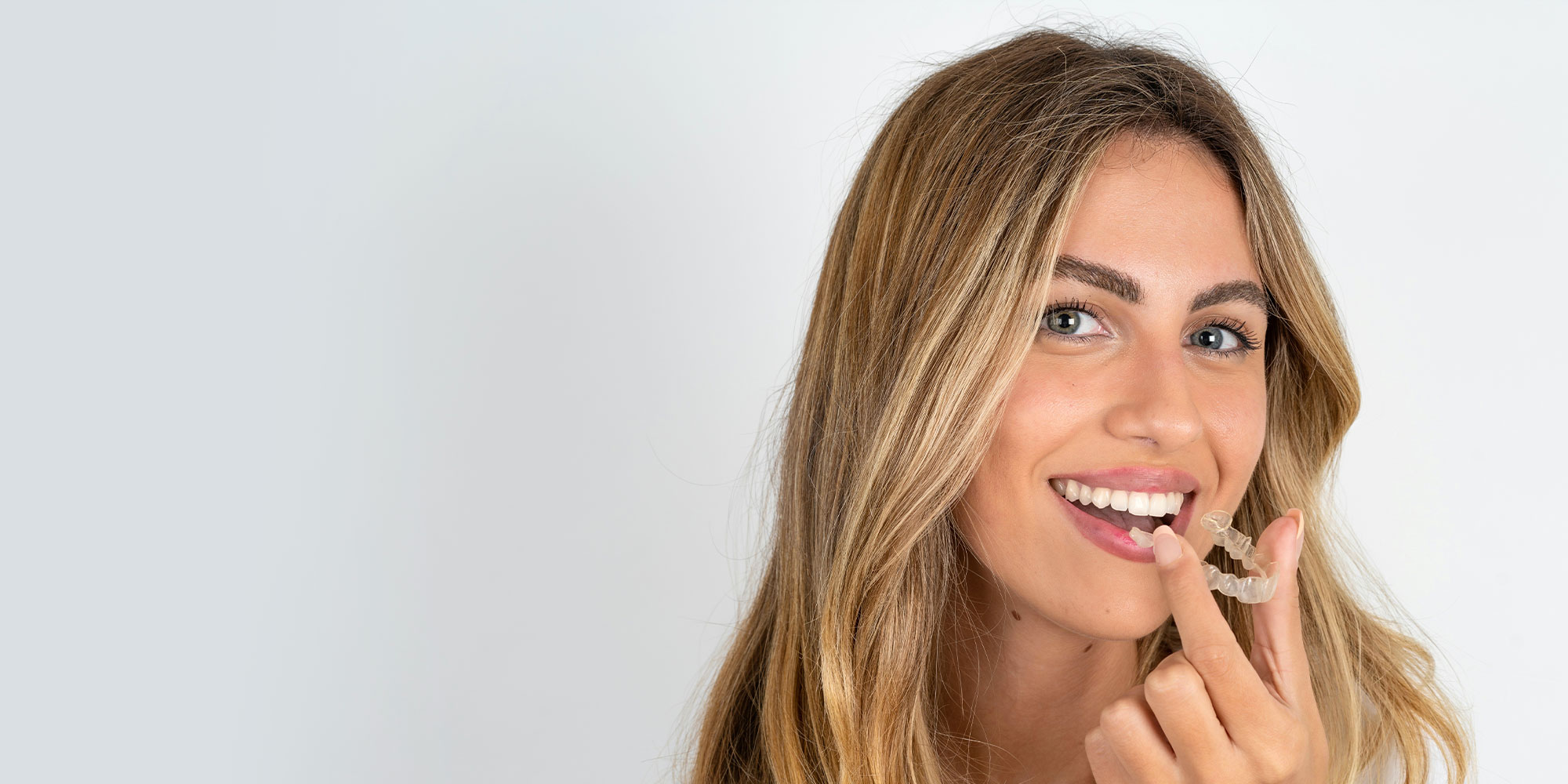 woman putting in invisalign her mouth
